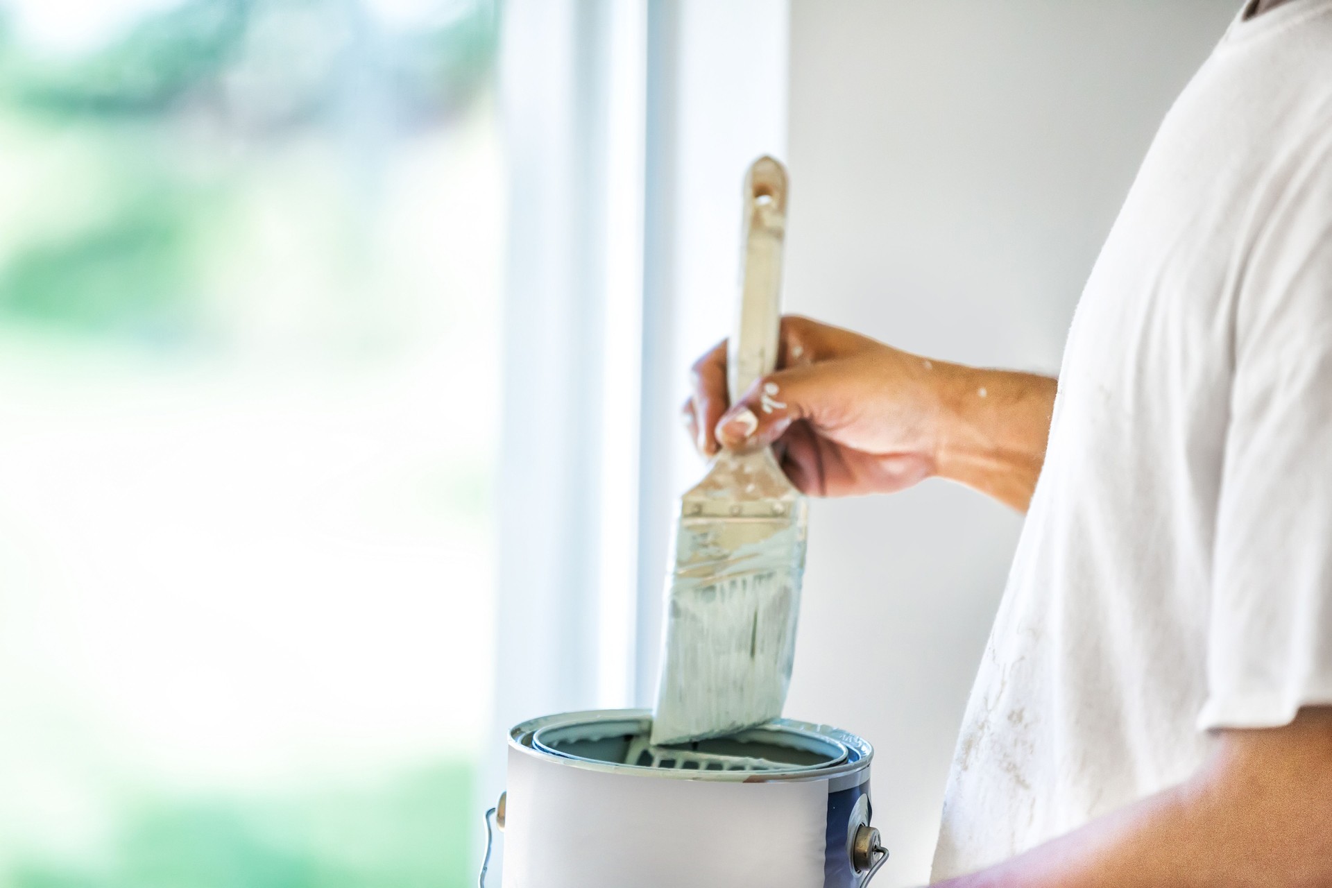 Painter dipping his brush in paint can